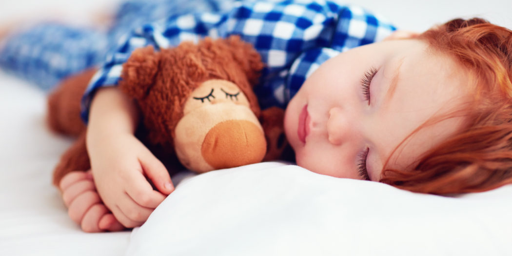 urocze rudowłose dziecko śpiące z maskotką