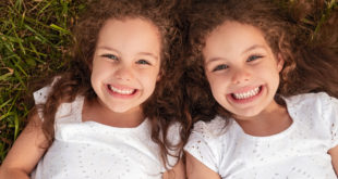 dwie śliczne dziewczynki bliźniaczki na trawie