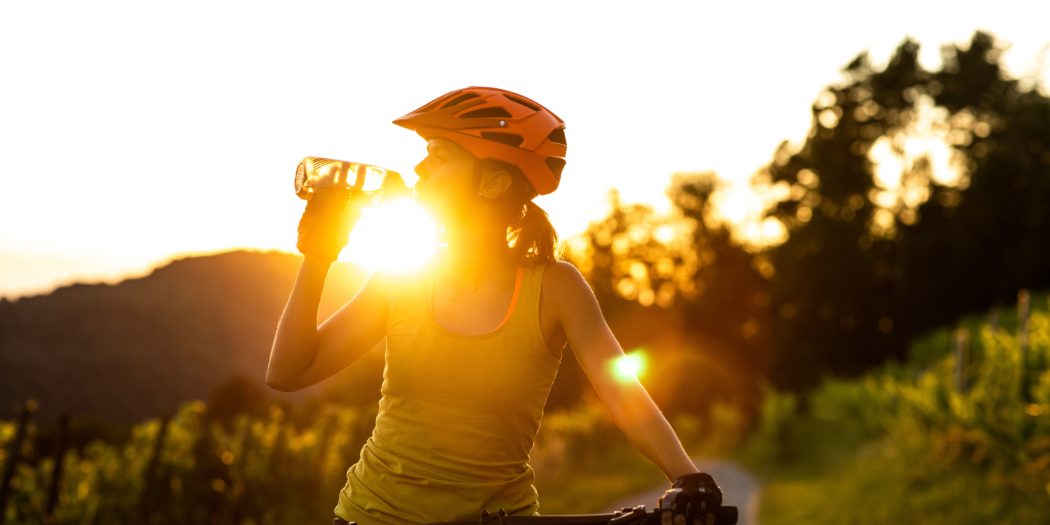 kobieta na rowerze pijąca wode z bidonu