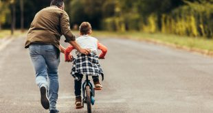 rodzic uczący dziecko jazdy na rowerze